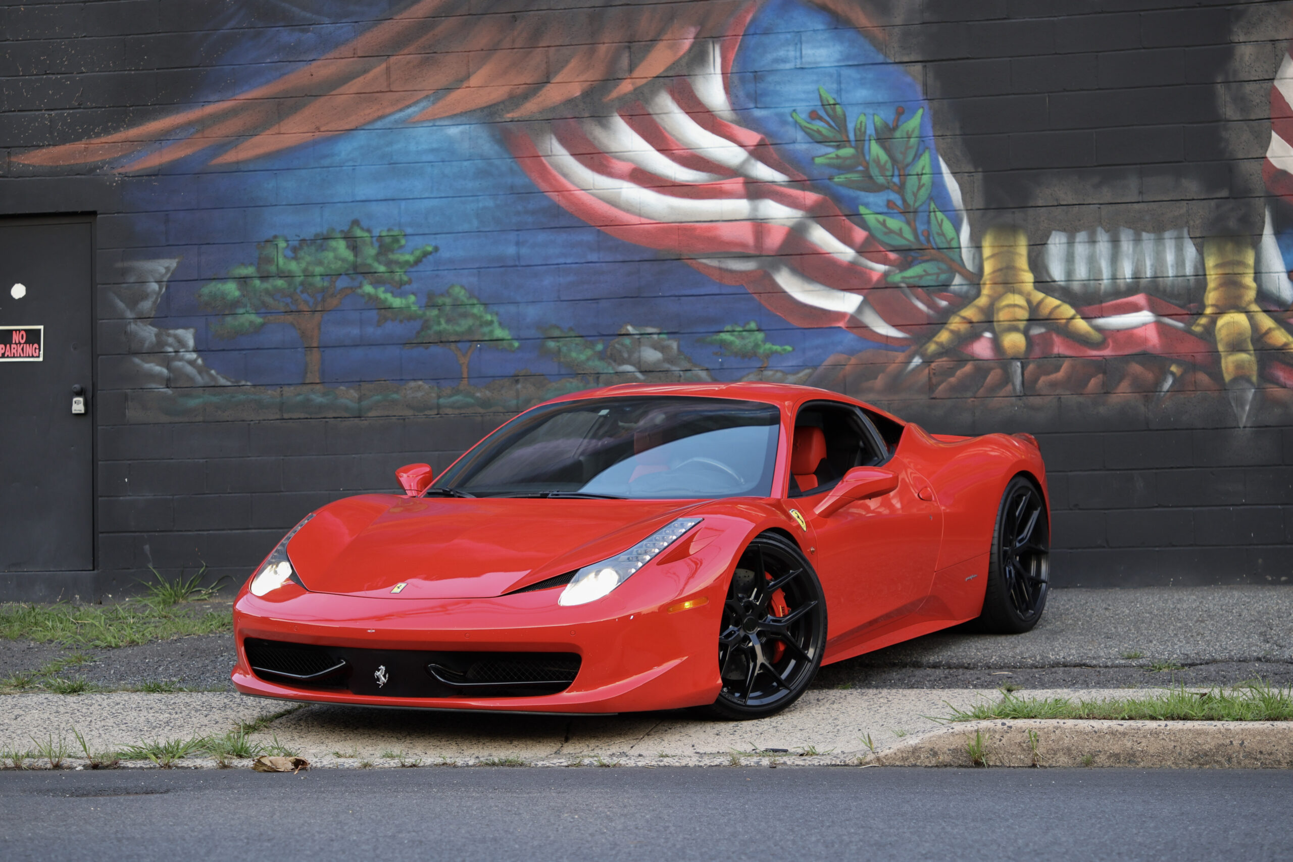 Red 2011 Ferrari 458 Italia parked in front of a mural